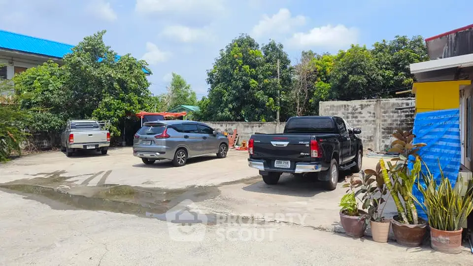 Spacious outdoor parking area with multiple vehicles and lush greenery.