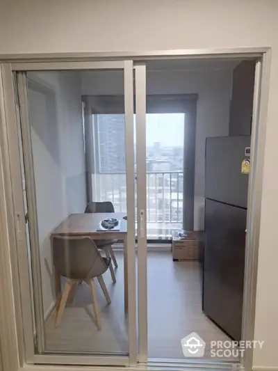 Modern apartment dining area with balcony view and sleek furniture.