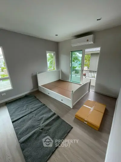 Spacious bedroom with large windows and modern flooring, featuring a daybed and air conditioning.