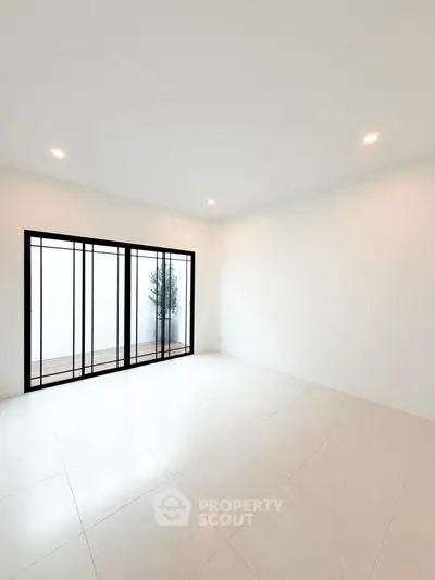 Spacious minimalist room with large sliding glass doors and bright natural light.