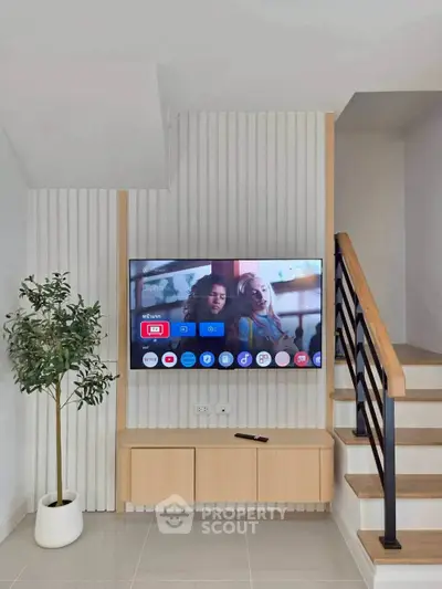 Modern living room with stylish TV setup and elegant staircase