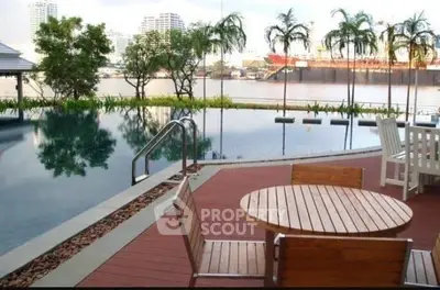 Luxurious riverside pool area with modern wooden deck and seating, offering stunning cityscape views.