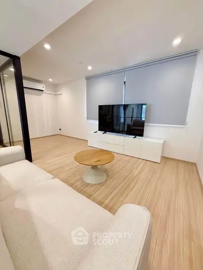 Modern living room with sleek design, featuring a large TV and minimalist furniture.