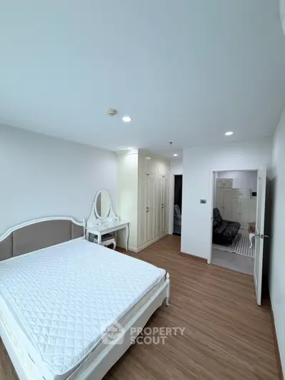Spacious bedroom with elegant furniture and wooden flooring in modern apartment