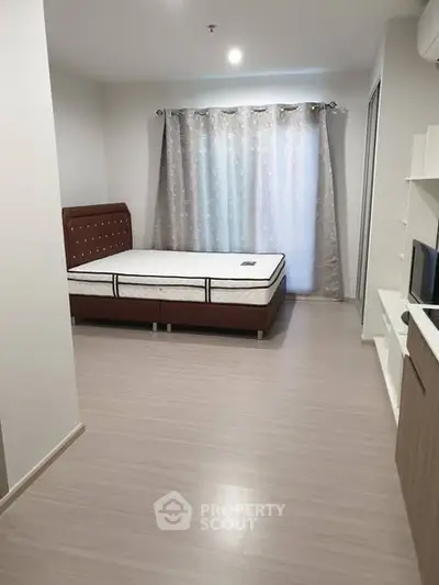 Spacious bedroom with modern decor and large window for natural light.