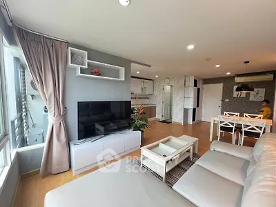 Spacious modern living room with open kitchen and dining area, featuring large windows and stylish decor.