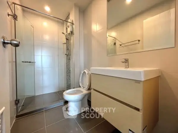 Modern bathroom with glass shower and sleek vanity in contemporary home.