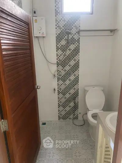 Compact bathroom with modern shower and toilet in a cozy home setting.