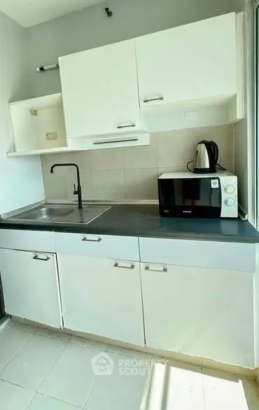 Modern compact kitchen with sleek white cabinets and appliances