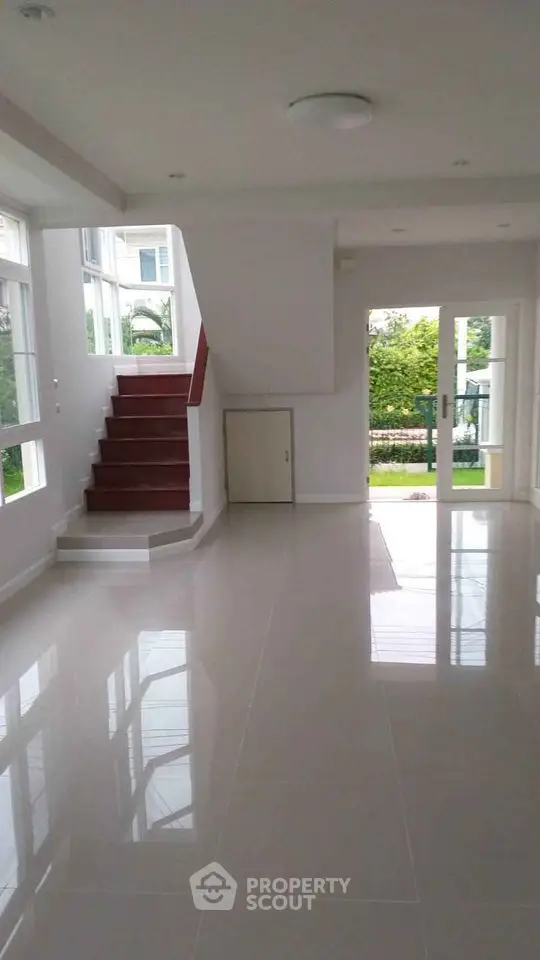 Spacious modern living room with glossy floors and staircase in bright home