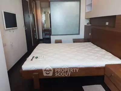Modern bedroom with wooden furniture and wall-mounted TV, ideal for cozy living.