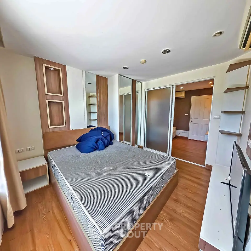 Modern bedroom with wooden flooring and built-in storage solutions.