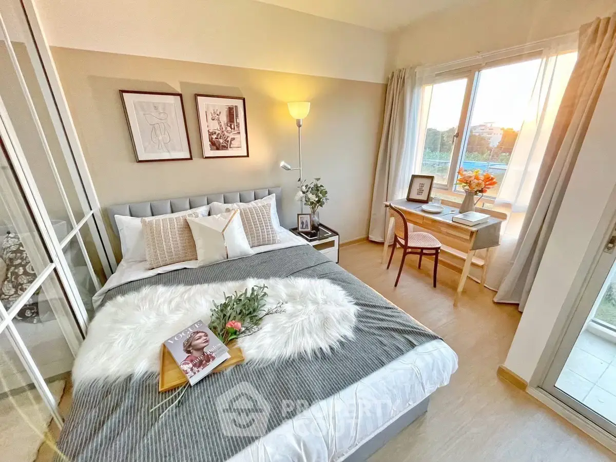 Cozy bedroom with stylish decor and natural light, featuring a small desk by the window.