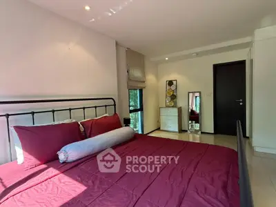 Spacious bedroom with modern decor and natural light in a stylish apartment.