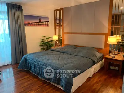 Spacious bedroom with elegant decor and cozy lighting, featuring a large bed and wooden flooring.