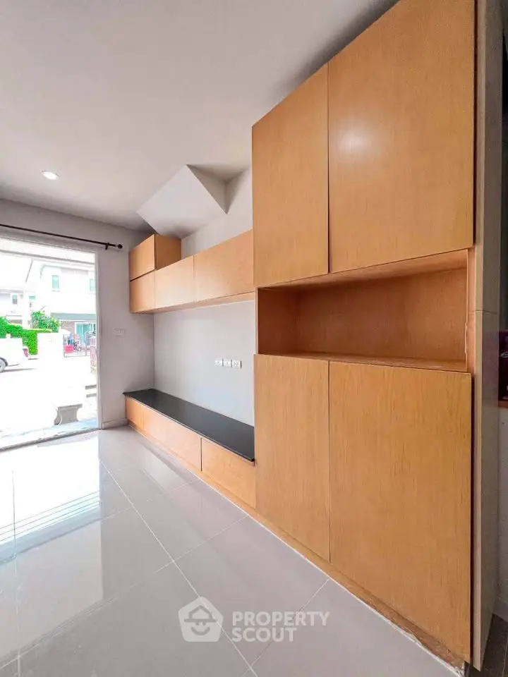 Spacious modern living room with built-in wooden cabinets and glossy tile flooring.