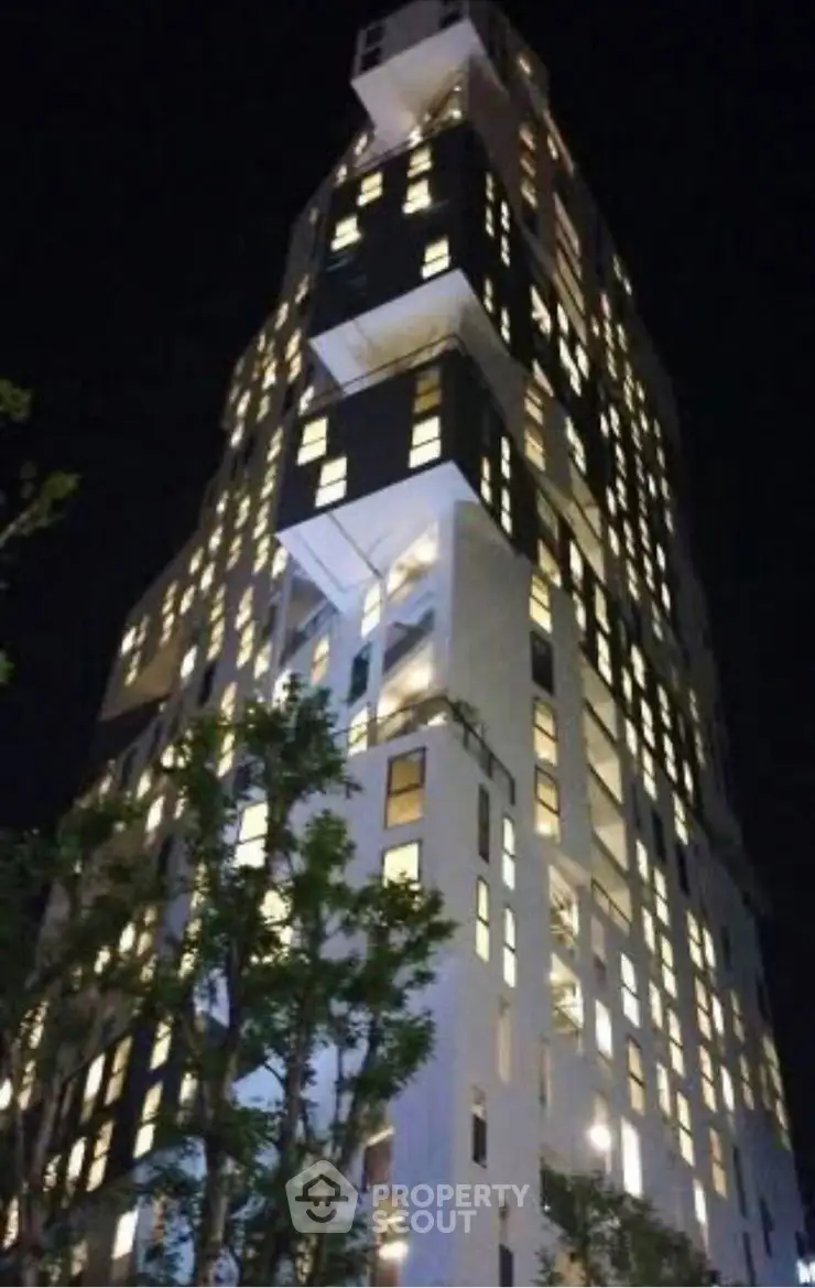 Stunning modern high-rise building illuminated at night with unique architectural design.