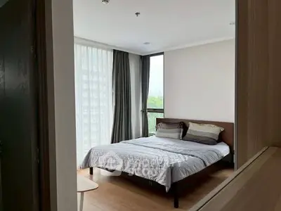 Spacious bedroom with large windows and modern decor in a high-rise apartment.