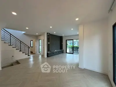 Spacious modern living room with large windows and elegant staircase