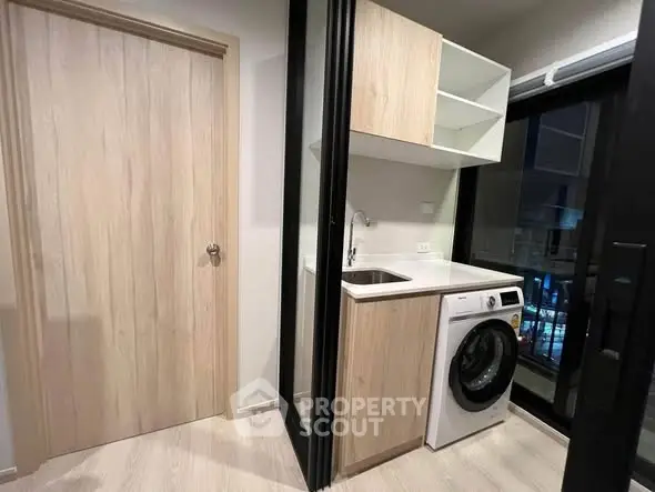 Modern compact laundry area with washing machine and storage cabinets in sleek apartment.