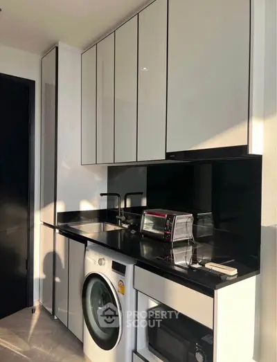 Modern kitchen with sleek cabinetry, washing machine, and appliances in a compact layout.