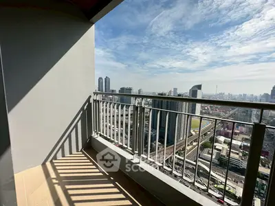 Stunning city view from a high-rise balcony with modern railing and clear blue sky.