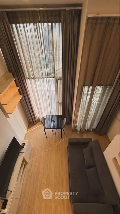 Modern loft-style living room with high ceilings and large windows