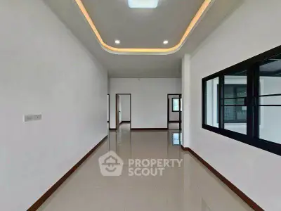 Spacious modern living room with sleek ceiling design and large windows.