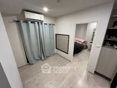 Modern apartment interior with bedroom and air conditioning, featuring light wood flooring and stylish curtains.