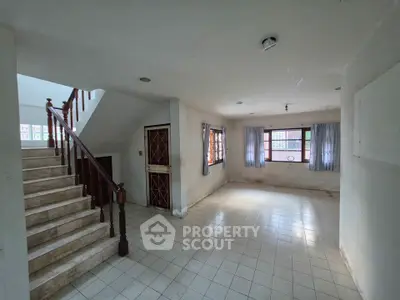 Spacious interior with tiled flooring and staircase, ideal for customization.