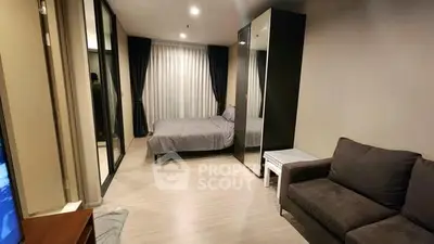 Modern bedroom with mirrored closets and cozy seating area