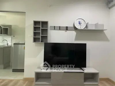 Modern living room with sleek TV stand and wall-mounted shelves, adjacent to a contemporary kitchen.