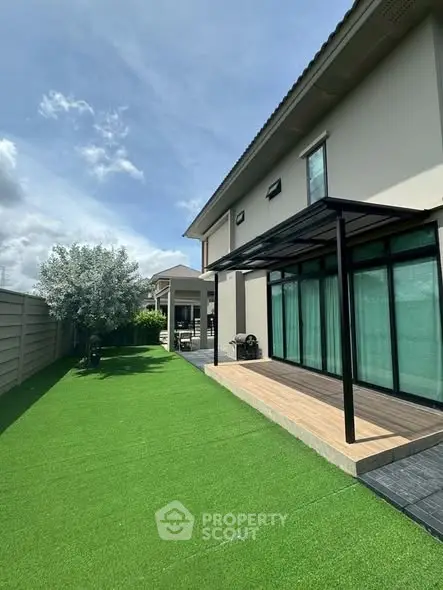 Modern house with lush green garden and patio, perfect for outdoor relaxation.