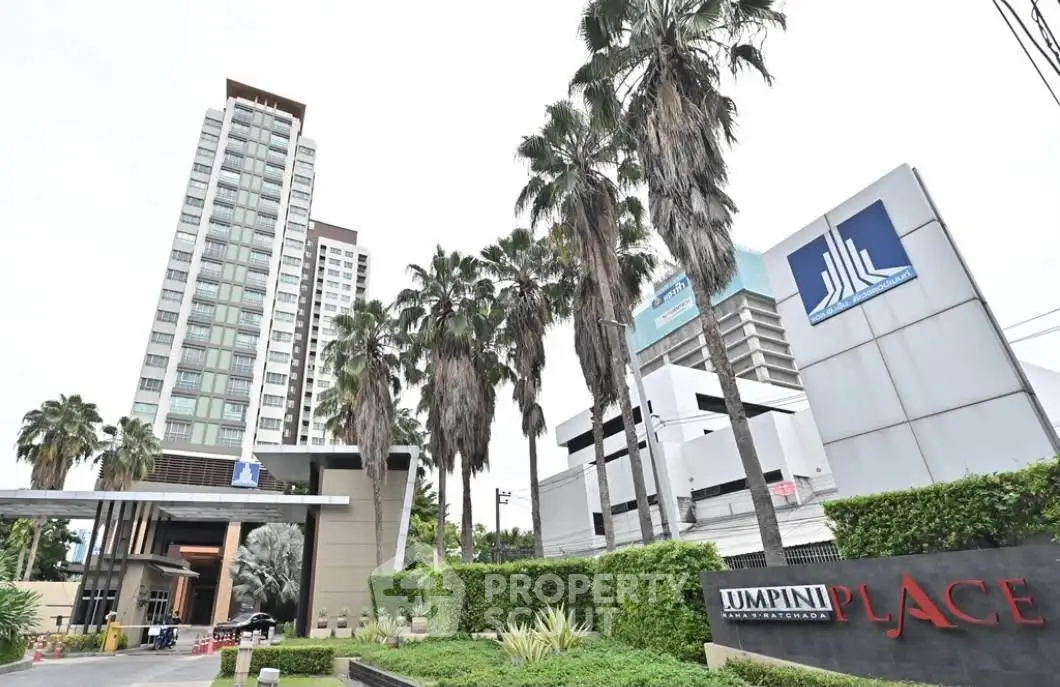 Modern condominium entrance with lush greenery and tall palm trees