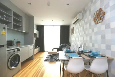 Modern open-plan living room with kitchen and dining area, featuring stylish decor and natural light.