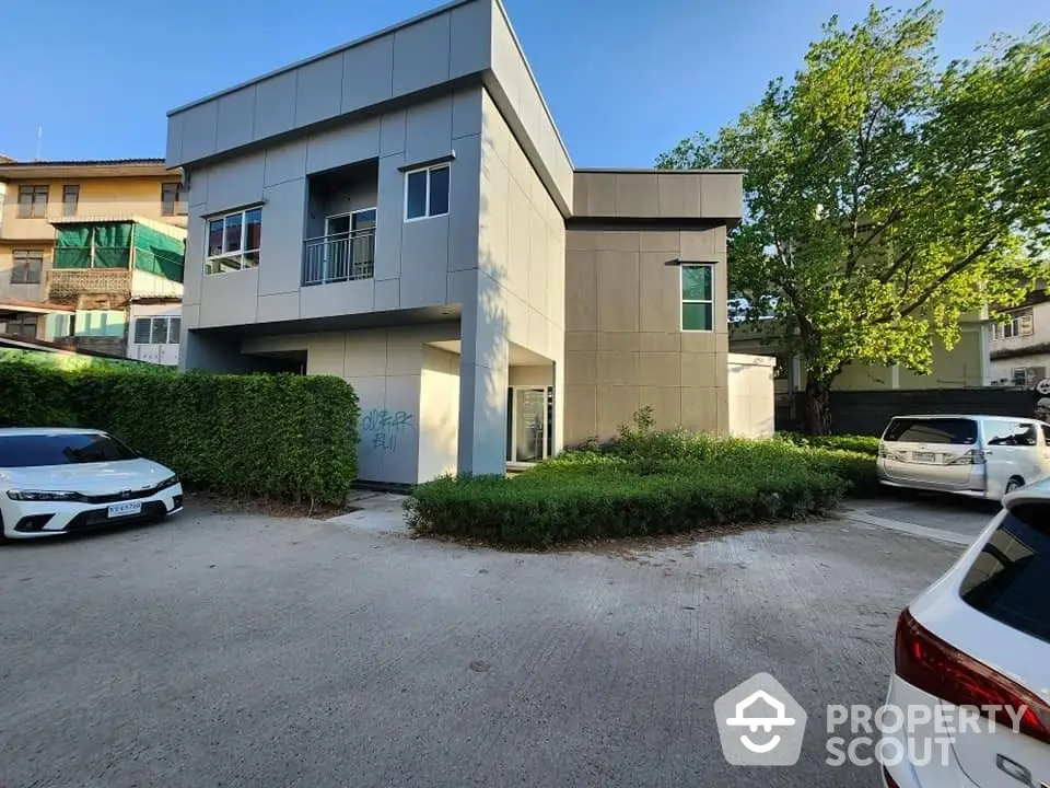 Modern two-story building with ample parking space and lush greenery, offering a blend of urban convenience and serene living.