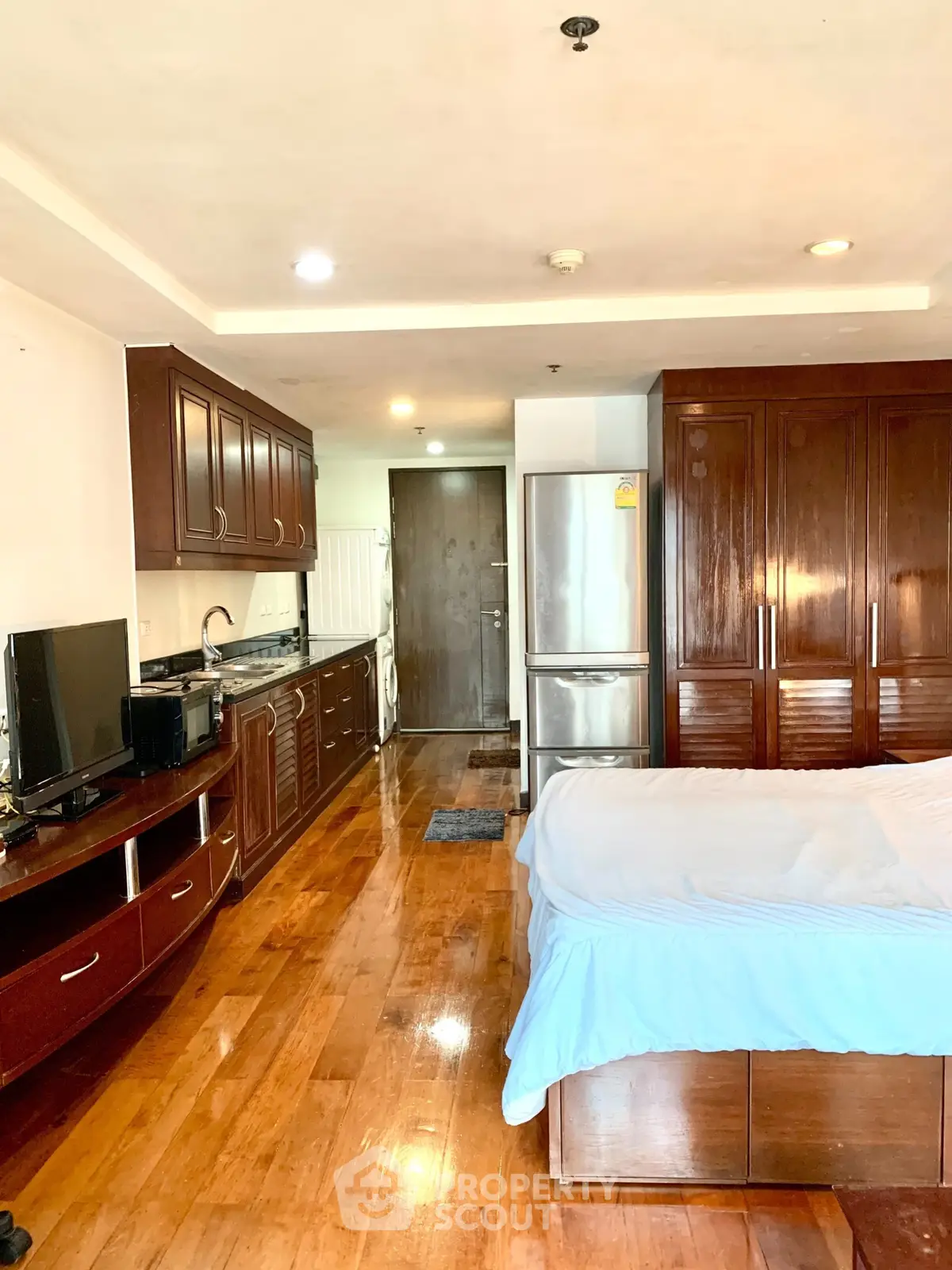 Spacious studio apartment with wooden flooring and modern kitchen appliances.