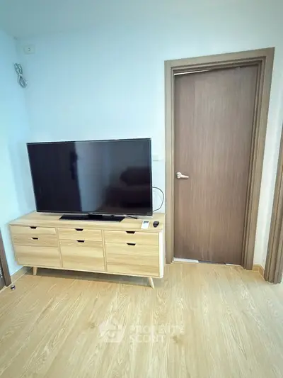 Modern living room with sleek TV stand and flat-screen TV, showcasing minimalist design and wooden flooring.