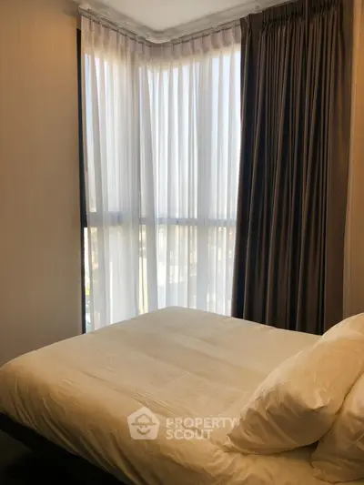 Cozy bedroom with large windows and elegant curtains, perfect for natural light lovers.