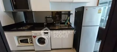 Modern kitchen with appliances including fridge, washing machine, and microwave in compact layout.