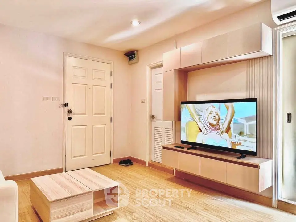 Modern living room with wooden flooring and stylish TV unit in a cozy apartment.
