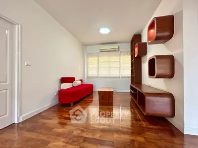 Modern living room with sleek wooden shelves and vibrant red sofa, perfect for stylish urban living.