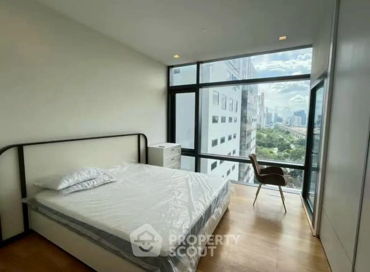 Modern bedroom with large windows offering stunning city views and natural light.