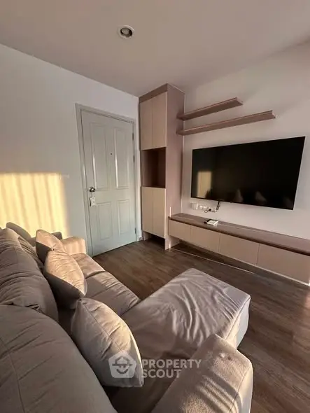 Modern living room with cozy sofa, wall-mounted TV, and stylish shelving in warm natural light.