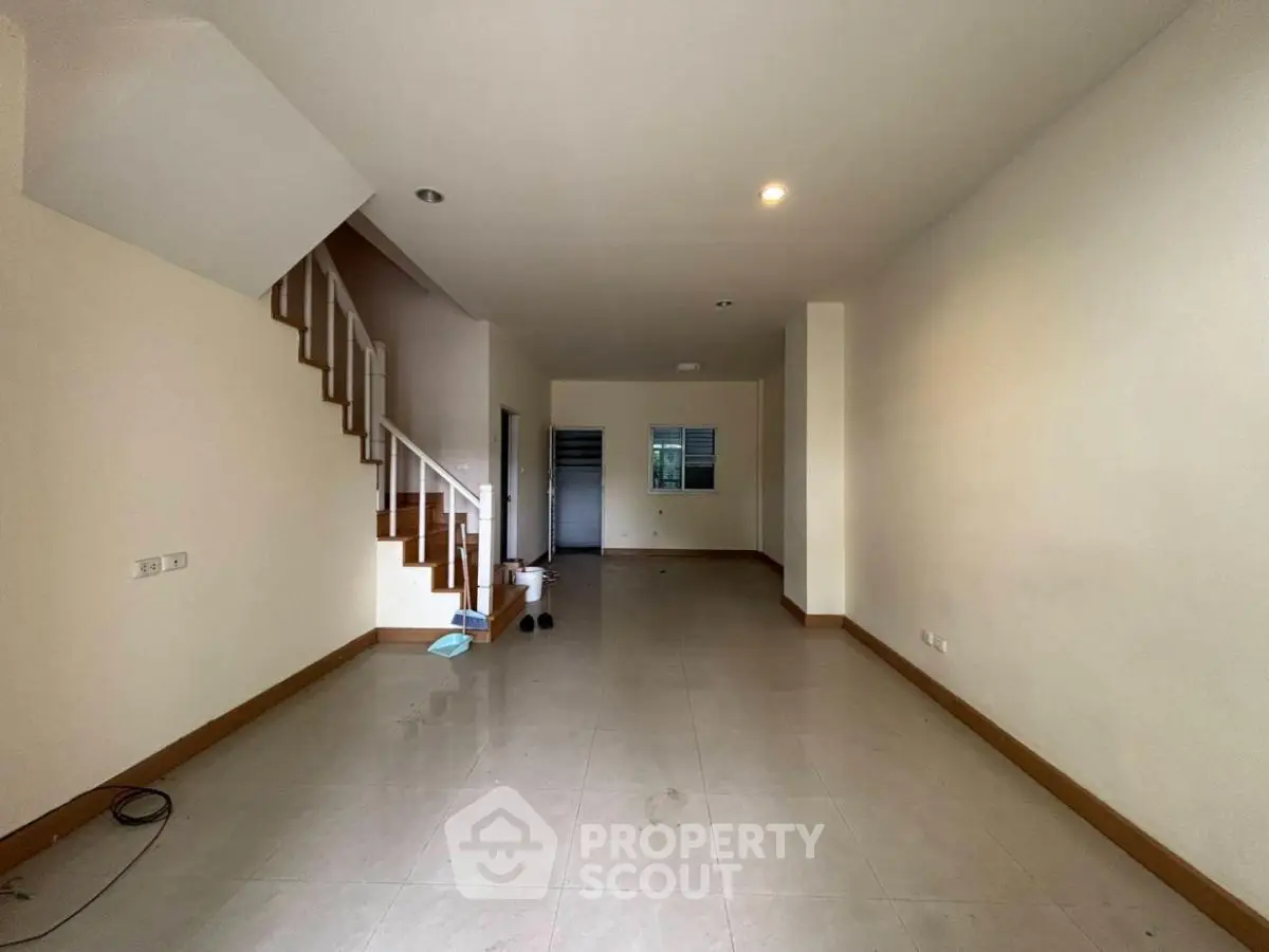 Spacious empty living room with staircase and tiled flooring