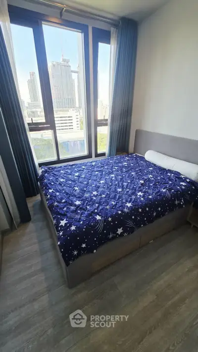Modern bedroom with large window offering city view, featuring stylish bed and elegant flooring.