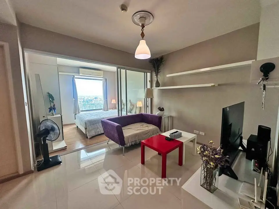 Modern living room with open layout and view into bedroom, featuring sleek furniture and stylish decor.