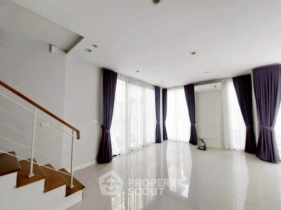 Spacious living room with large windows and elegant curtains
