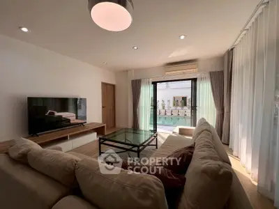 Spacious living room with modern decor and large windows leading to a balcony.