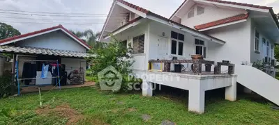 Charming elevated white house with red roof and lush green garden